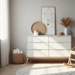 Een hyperrealistische foto van een serene Scandinavische kinderkamer met natuurlijk ochtendlicht, een witte MALM-ladenkast tegen een zachte grijze muur, een vintage rieten schommelstoel, en een crème wollen vloerkleed met geometrische patronen. Babybenodigdheden zijn zorgvuldig georganiseerd op de ladekast, met een geweven mand voor luiers, en een minimalistische mobiel die delicate schaduwen werpt. Decoraties omvatten gedroogd pampasgras in een keramisch vaasje en aardetinten in de styling.