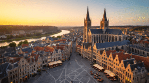 Aerial view of Maastricht's Vrijthof square at golden hour, featuring the Sint-Servaasbasiliek and Sint-Janskerk towers, cobblestone streets, outdoor cafes, the Maas river, lush Frontenpark, and ENCI quarry cliffs bathed in sunset light.