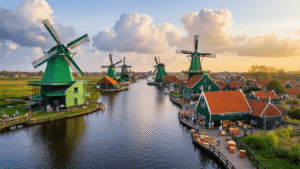 Zaanse Schans: De Verborgen Nederlandse Tijdcapsule Die Je Niet Mag Missen Aerial view of Zaanse Schans featuring green wooden windmills, traditional houses, visitors exploring workshops, and a working miller, all under a dramatic sky during golden hour.
